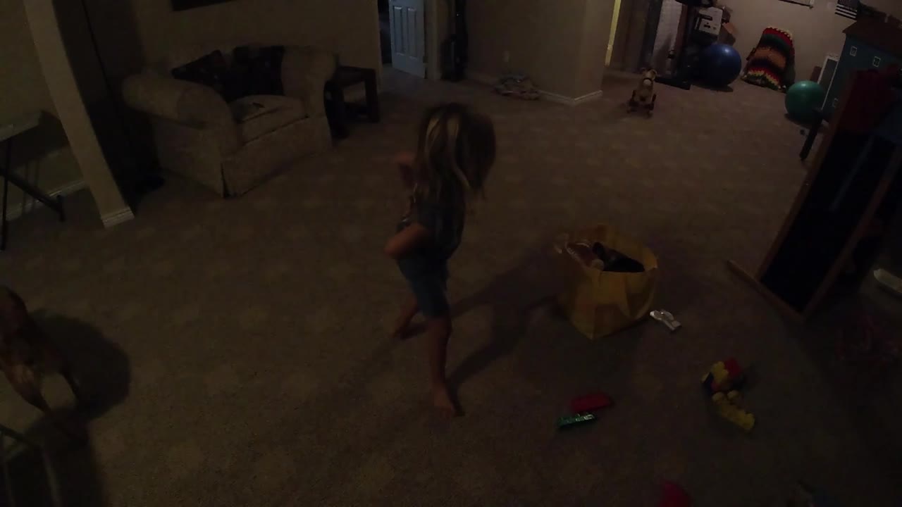 Young girl stepping past a yellow bag in a living room.