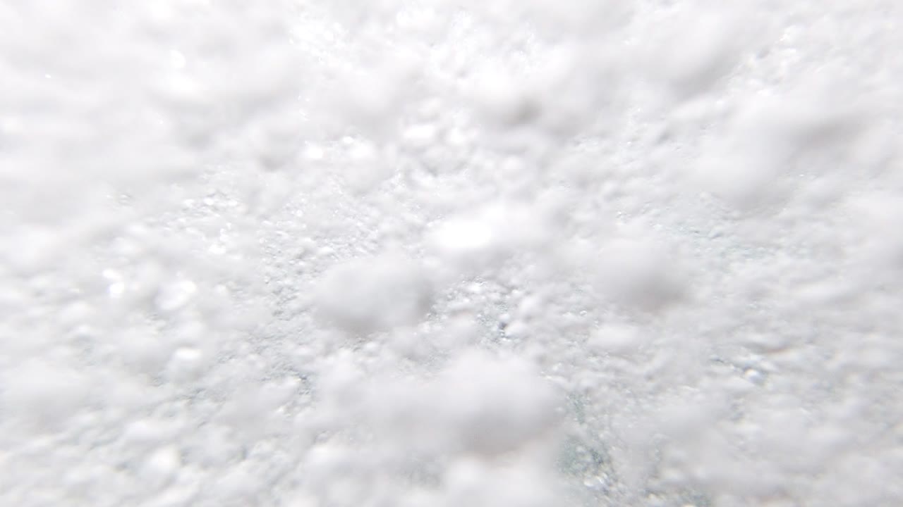 Extreme close-up of white seafoam bubbles at the ocean surface in Los Cabos, Mexico, 2019, with teal-gray water visible in small gaps; no people visible