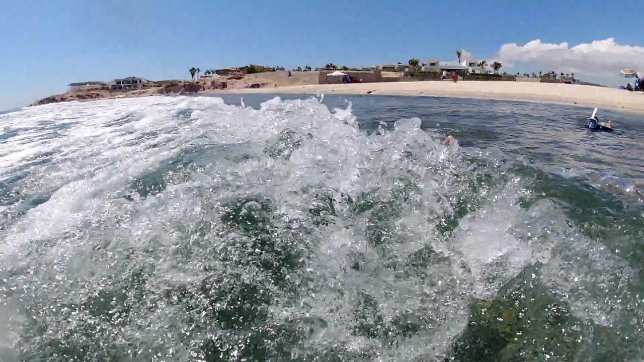 Foamy wave close to camera with beach in background.