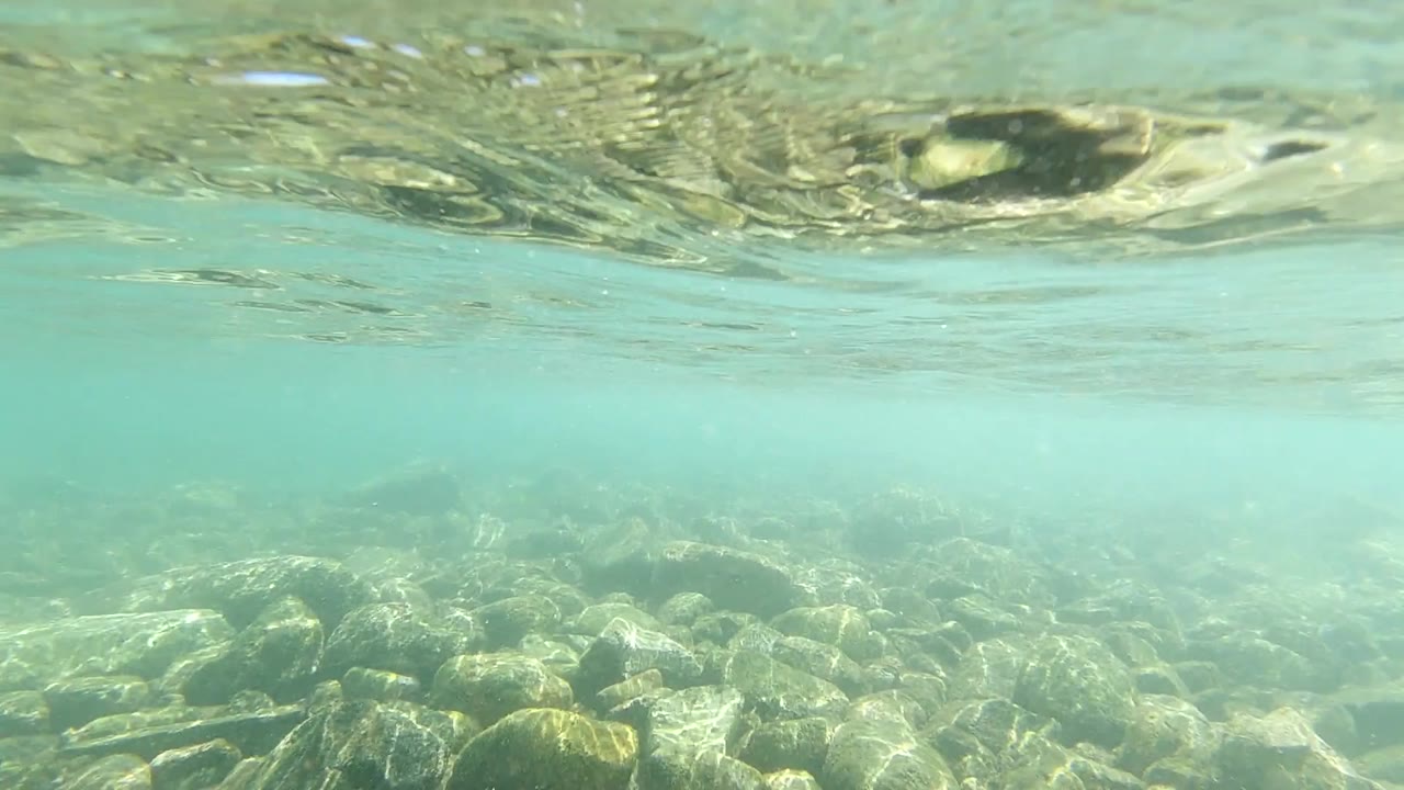 Underwater rocks and pale surface reflections in turquoise water.