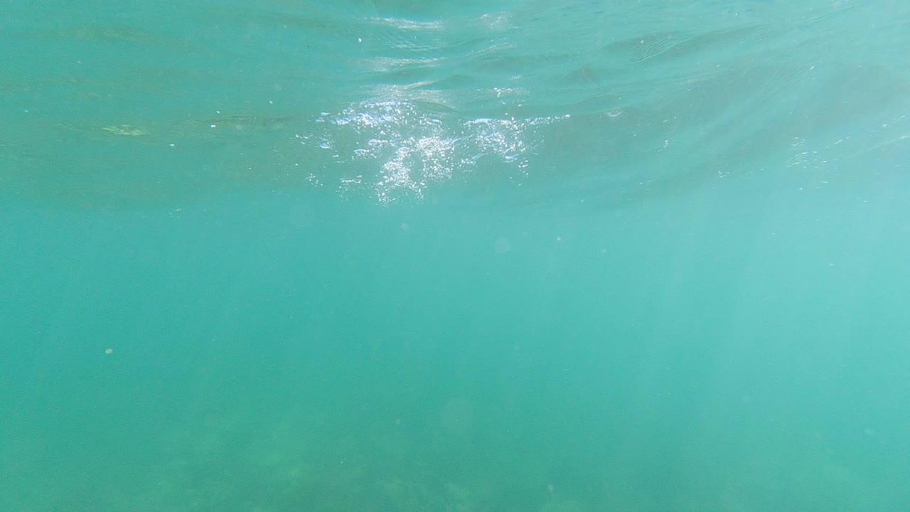 Los Cabos underwater frame with brighter surface highlights near the top center and hazy green water below, with no visible people.