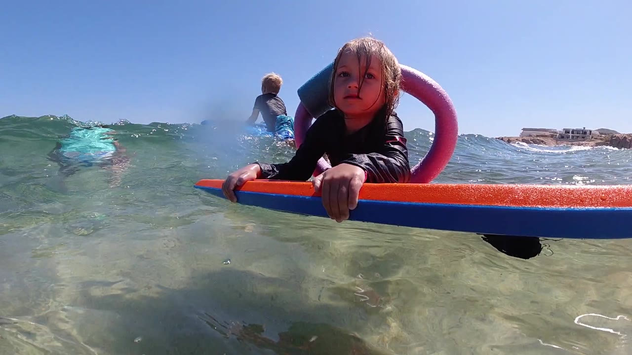 Girl holding an orange float in clear ocean water