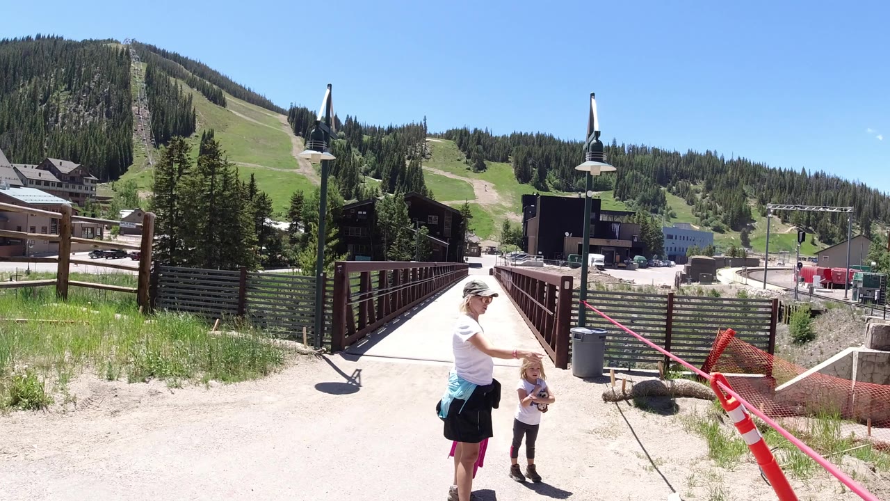 Woman and child standing near a pedestrian bridge at a mountain recreation area.