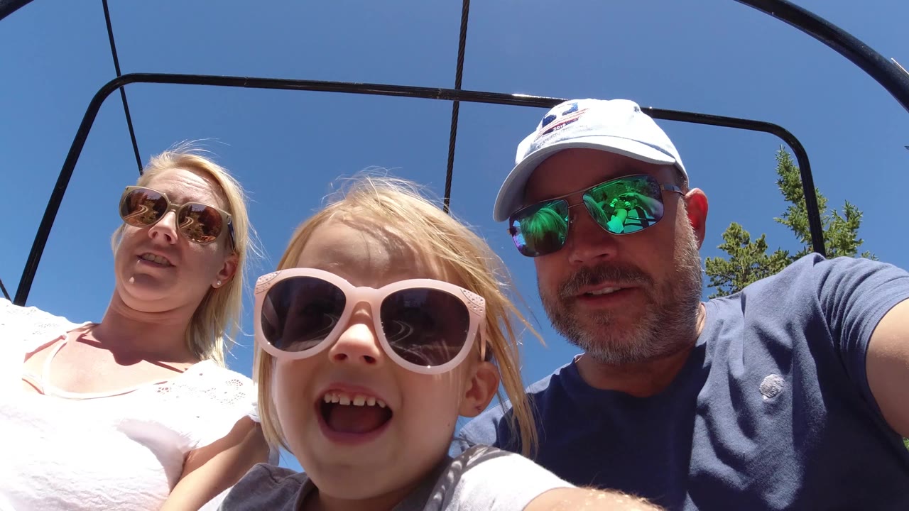 Child smiling between adults on a chairlift