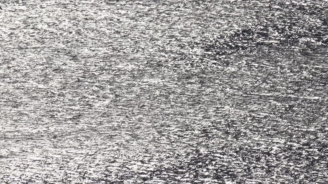 Open Malibu ocean water with bright sun glints clustering across the upper and middle frame, with no visible people.