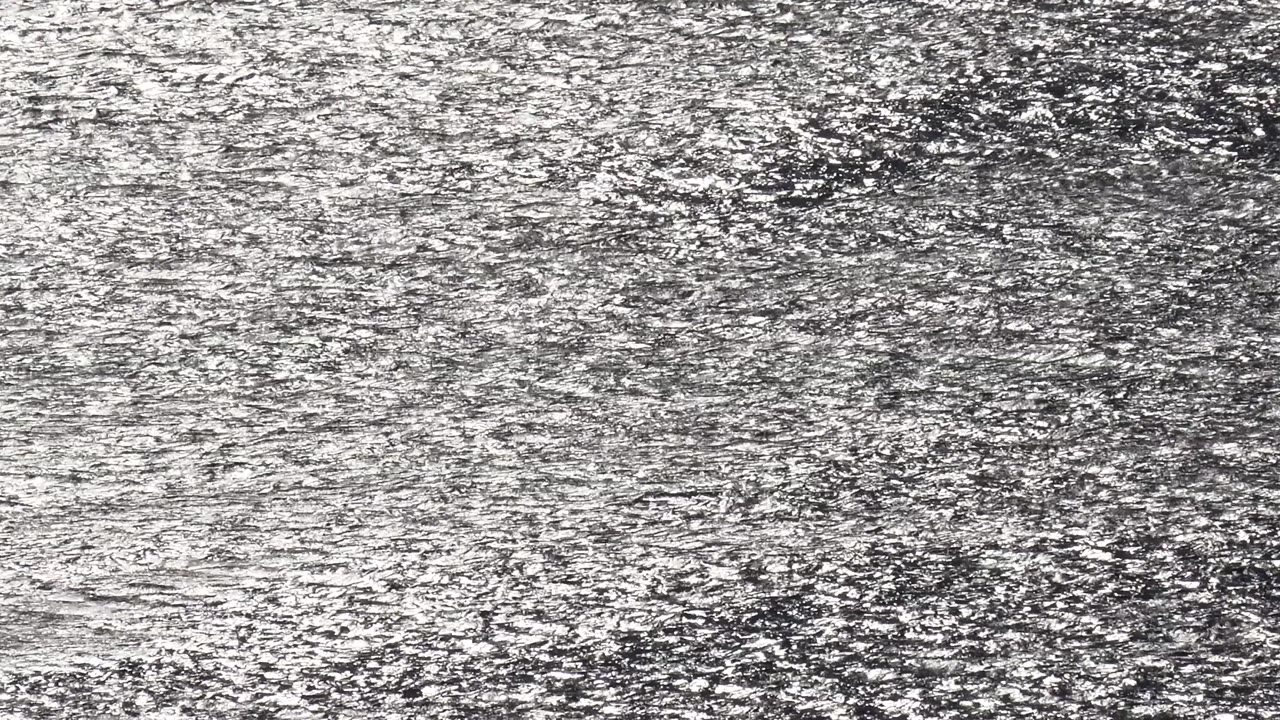 Malibu sea surface filled edge to edge by silver reflection bands and darker ripples, with no boats, shoreline, or visible people.