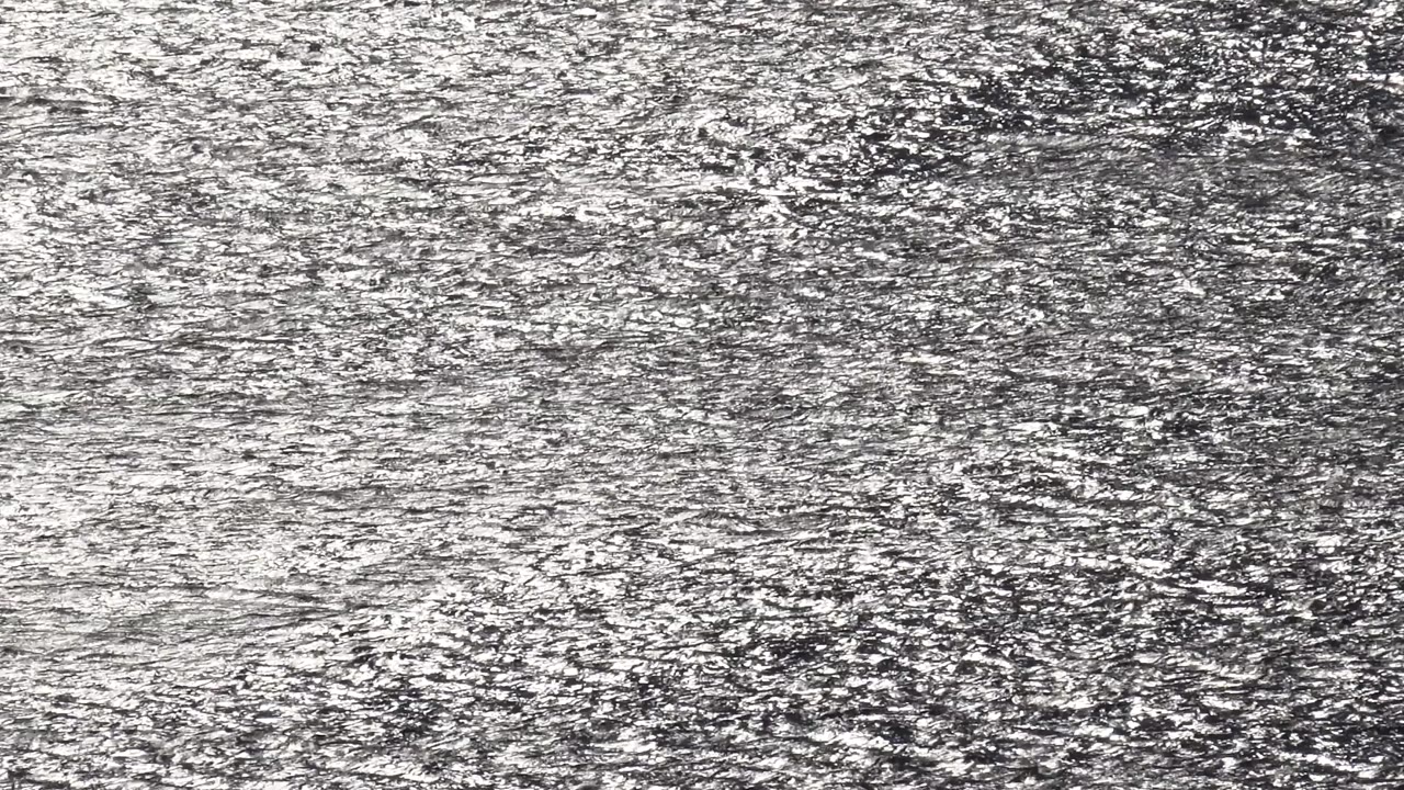 Tightly framed Malibu ocean water with scattered bright reflection lines moving across the rippled surface and no visible people.