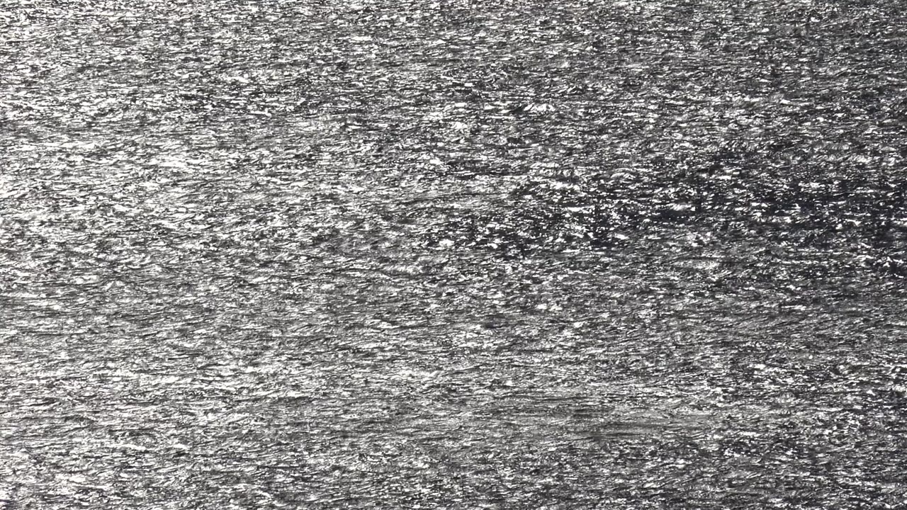 A tight Malibu, California abstract frame of gray and white water or grit texture, with no visible people or landmarks.