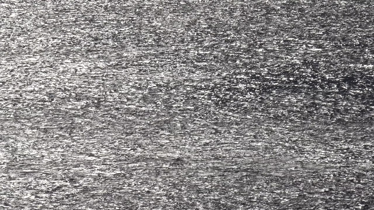 The Malibu frame shows uneven gray bands and white granular highlights across a tight water or grit surface, with no visible people.