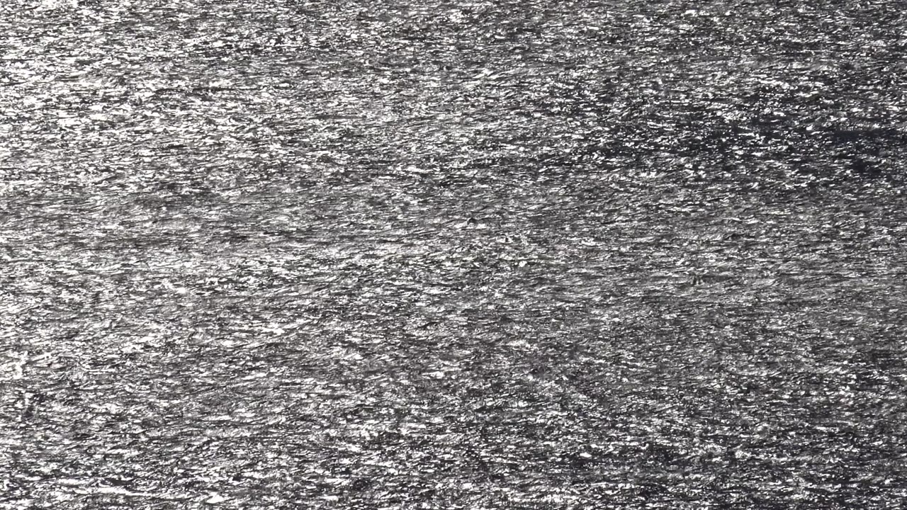 Mid-clip frame of the Malibu surface with small bright reflections scattered through the center and upper portion, with no visible people.