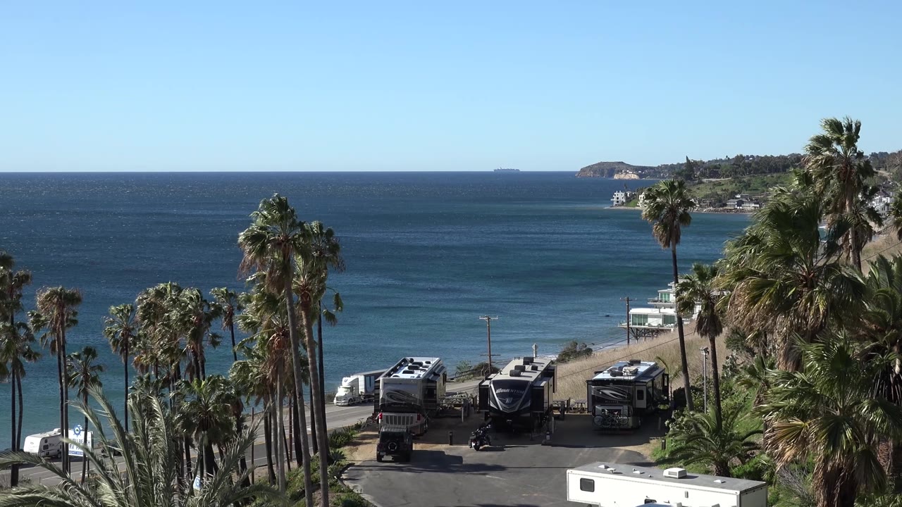 Beach parking area under palms beside blue ocean