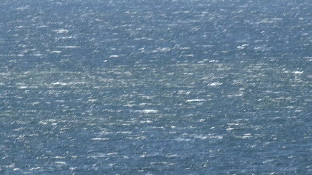 A close Malibu water surface shows brighter shimmer across the midframe, with no shoreline, boats, or visible people.
