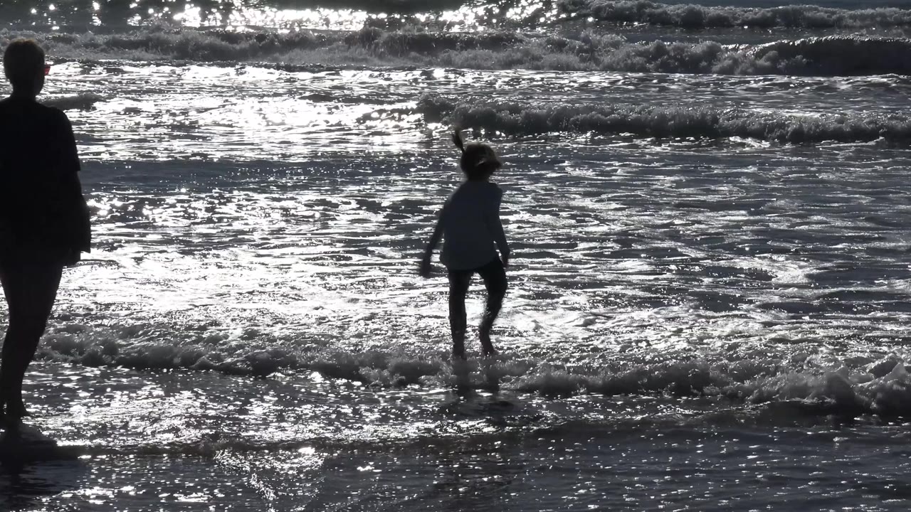 Adult woman watching a child in the waves.