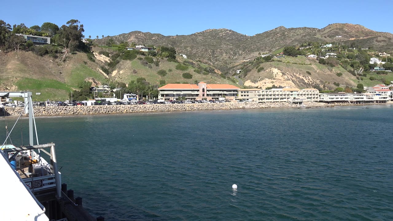 Waterfront buildings below hills with buoy in the ocean