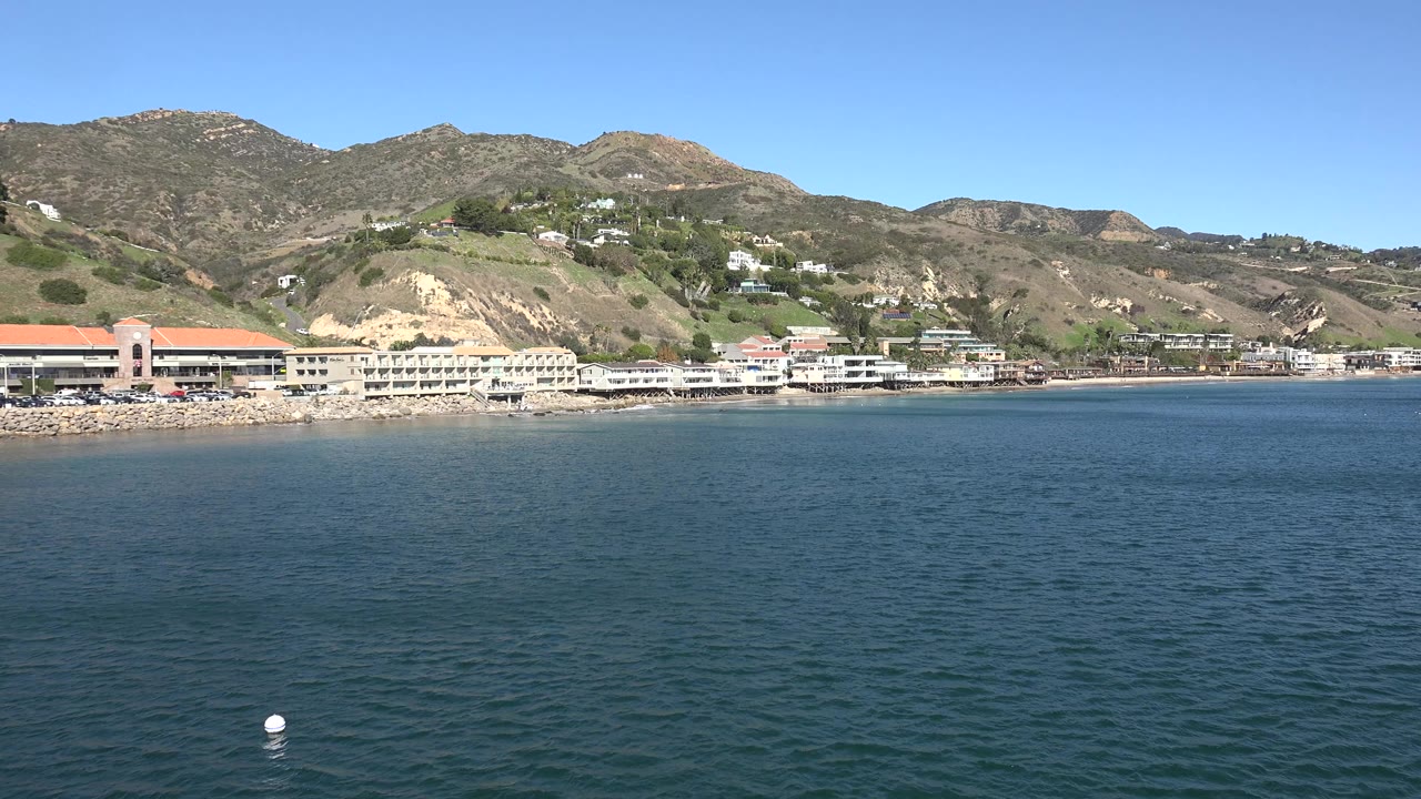 Malibu shoreline across water with beach buildings and hills