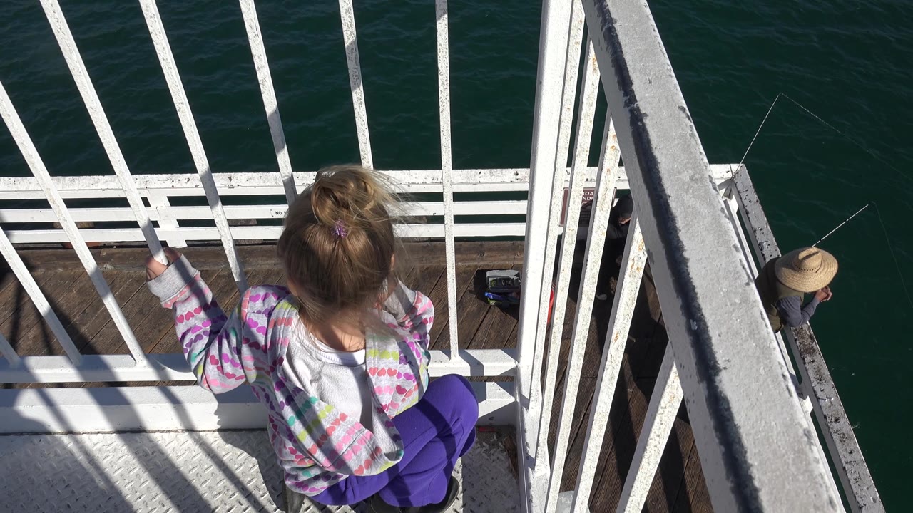 Overhead view of child on balcony with ocean below.