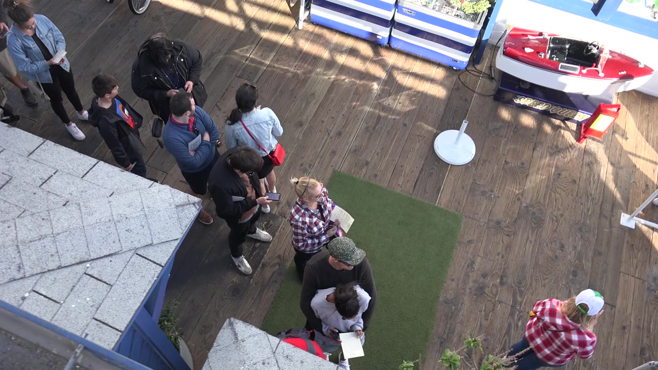 Group of adults on a deck viewed from above beside artificial turf.