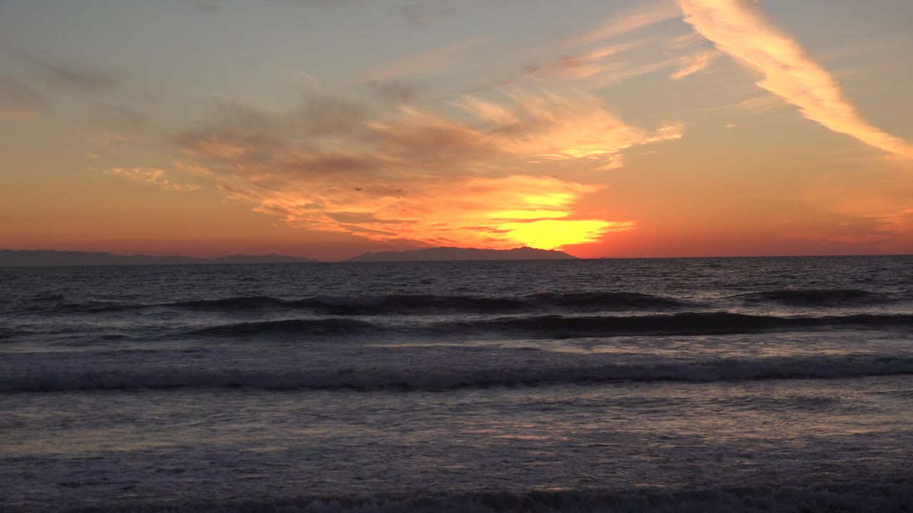 Orange sunset sky over dark surf