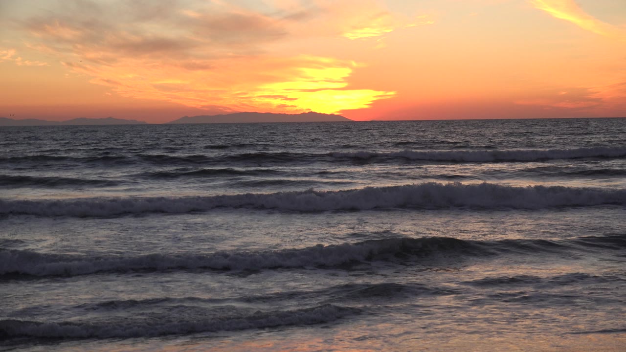 Ocean surf beneath red sunset clouds.