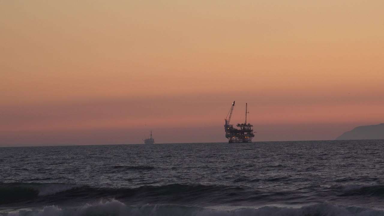 Dark waves below offshore boats at dusk.