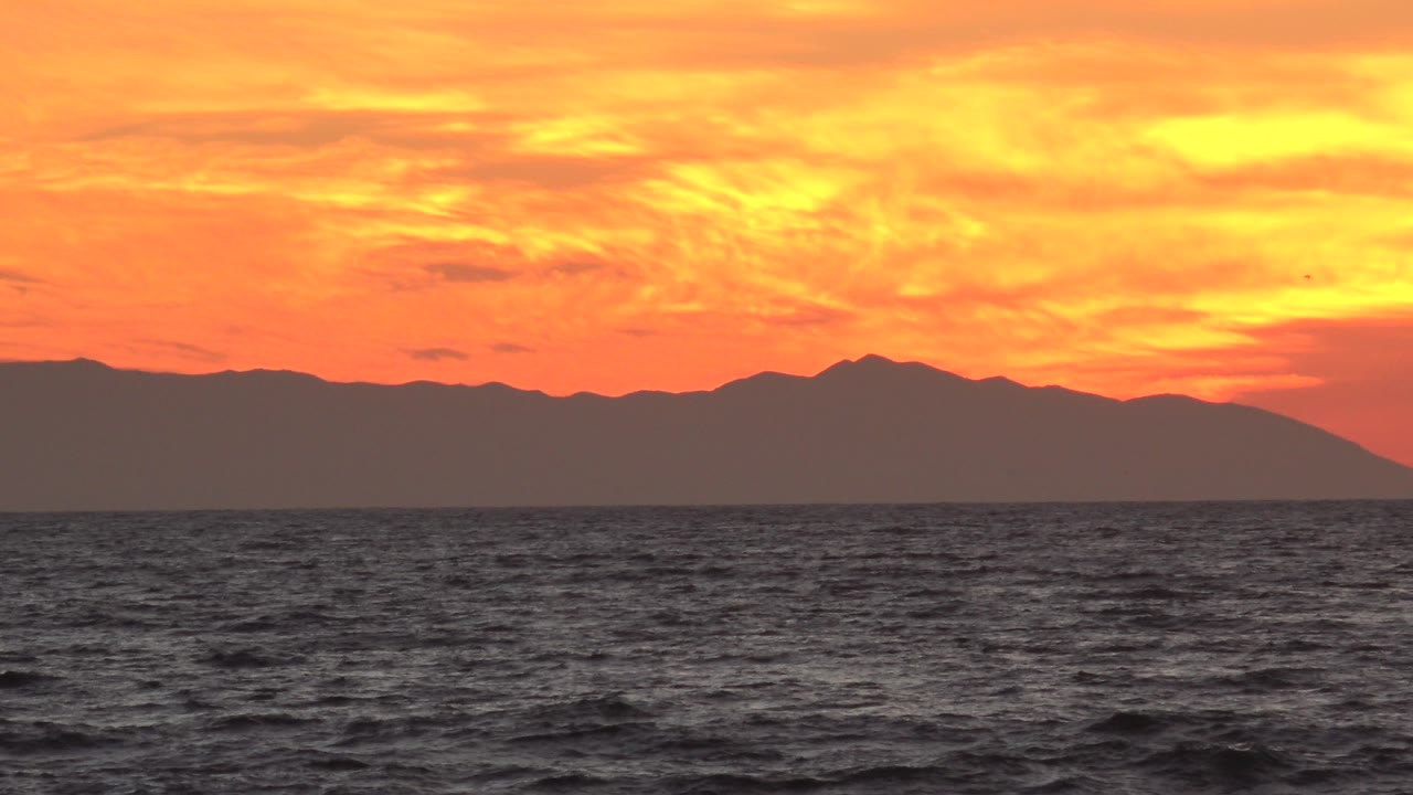 Dark Pacific water below a bright orange sky.