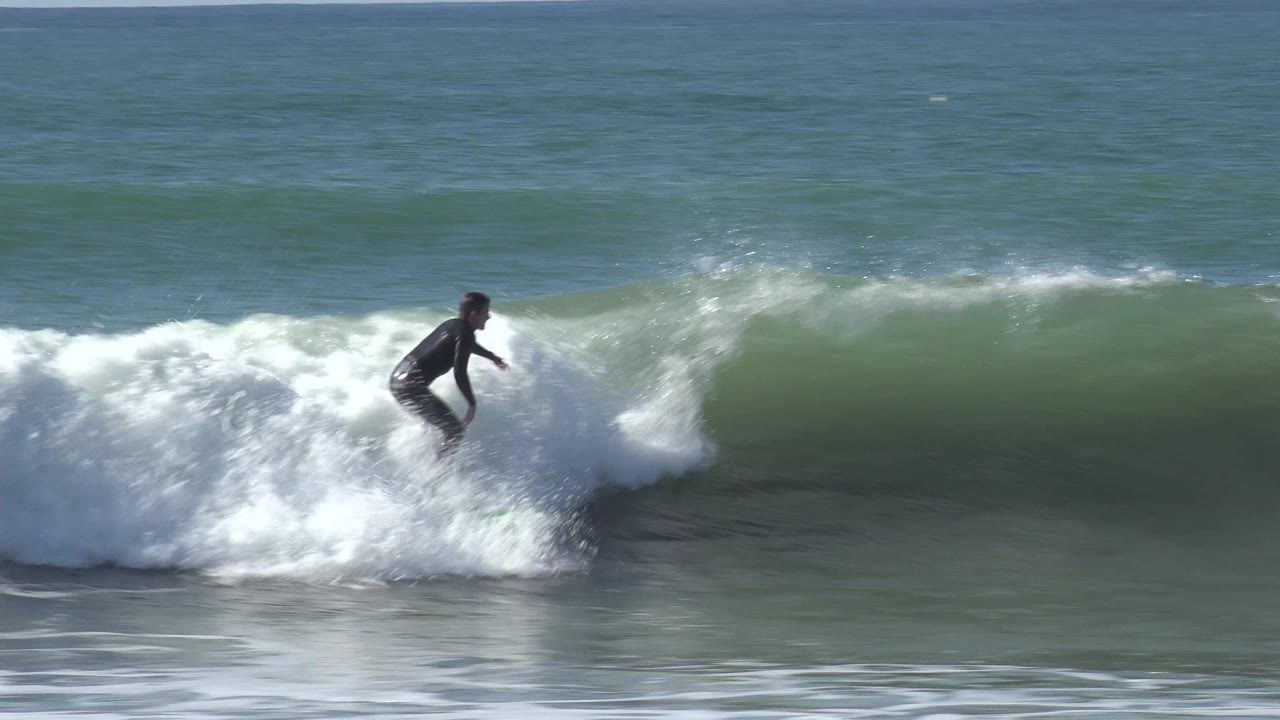 Surfer rides over churning whitewater near the wave shoulder.