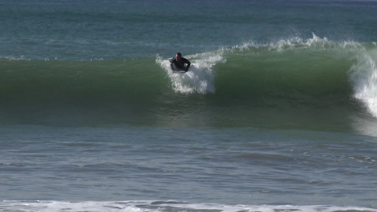 Surfer continues along the top of a breaking ocean wave.