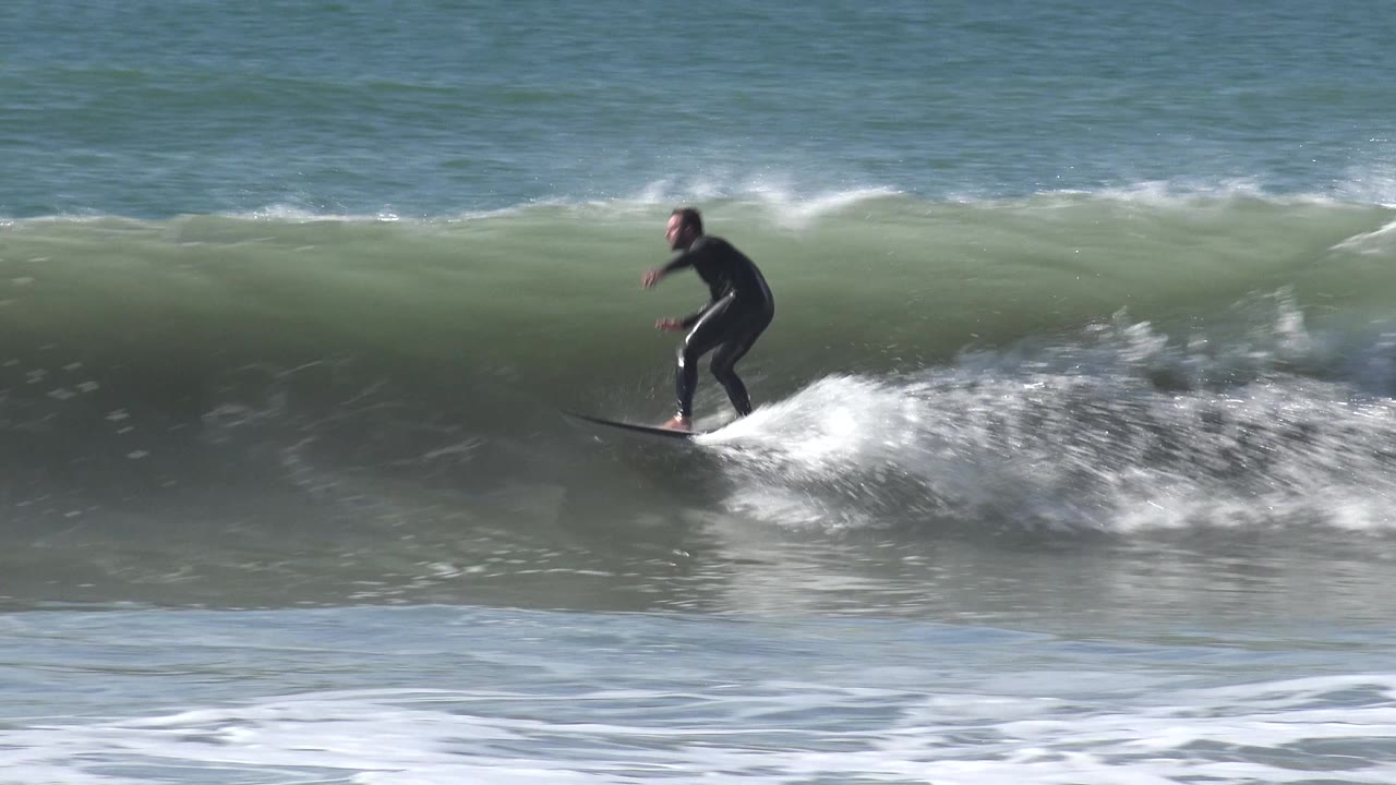 At Huntington Beach, California, the surfer rides left along a dark green wave face while white foam spreads across the lower edge of the frame.
