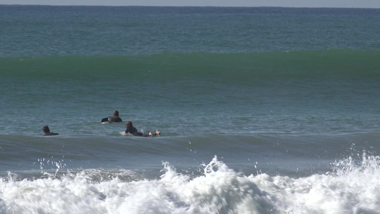 Three surfers waiting near an incoming wave