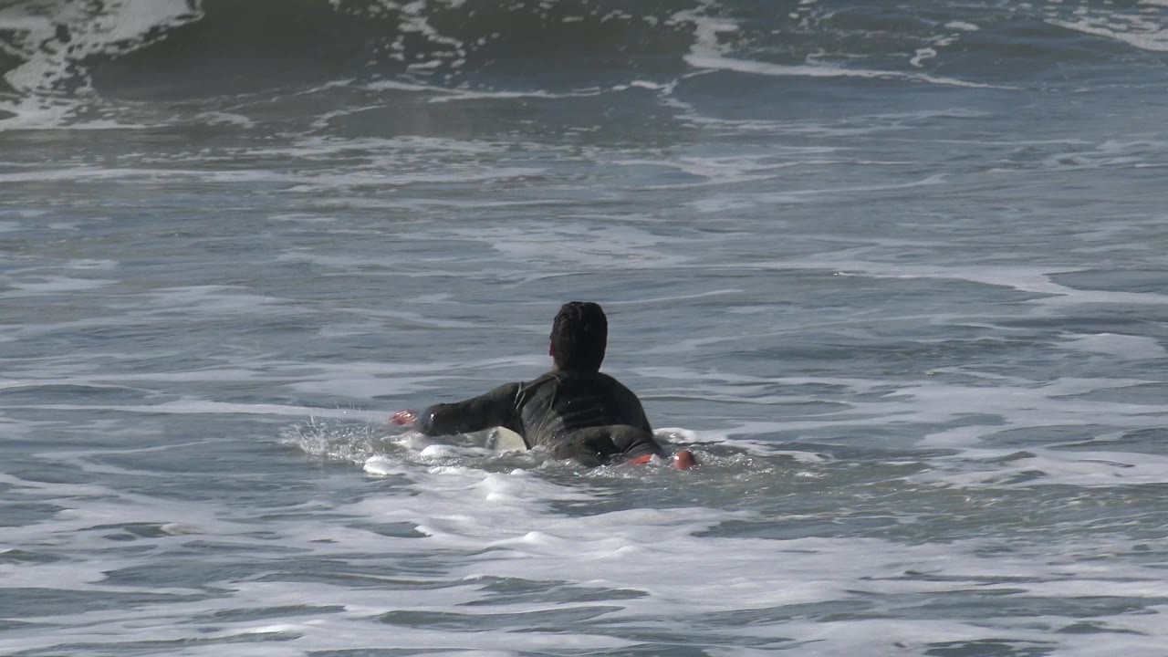 Swimmer low in frame with a wave forming ahead.