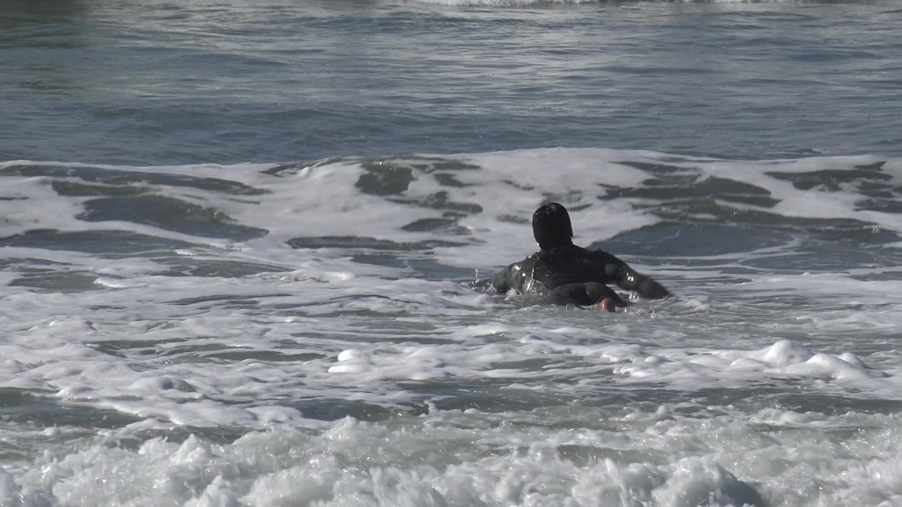 Surfer prone on board in foamy water