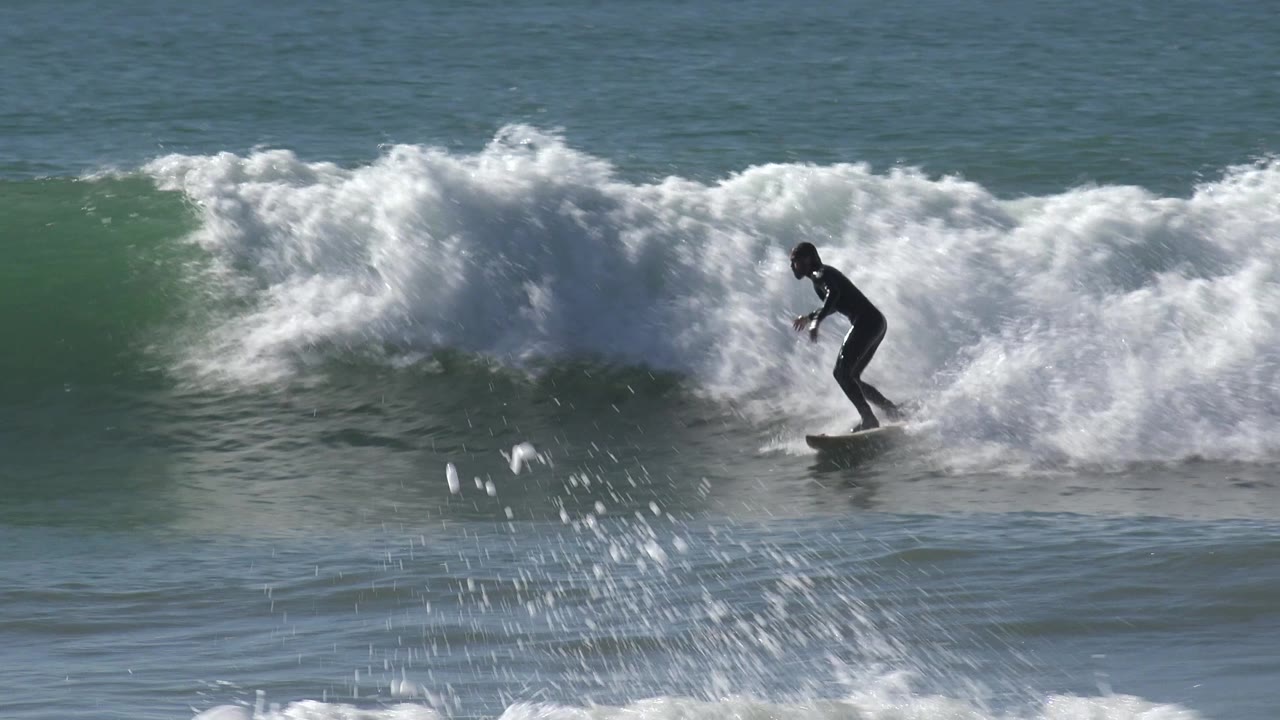 Surfer continues along the foamy wave face.