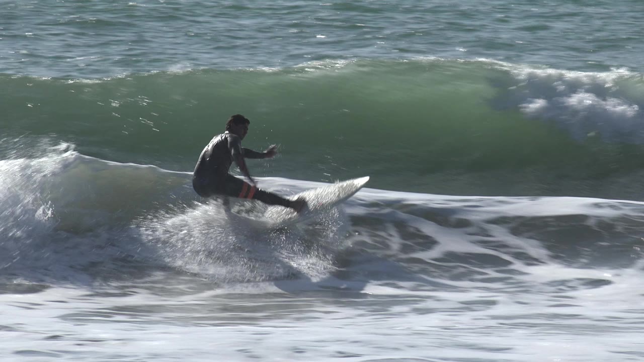 Surfer balances on a board as whitewater curls around him.