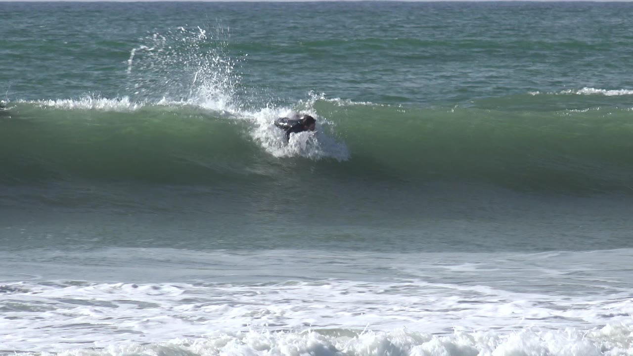 Surfer partly hidden by wave spray near the crest.