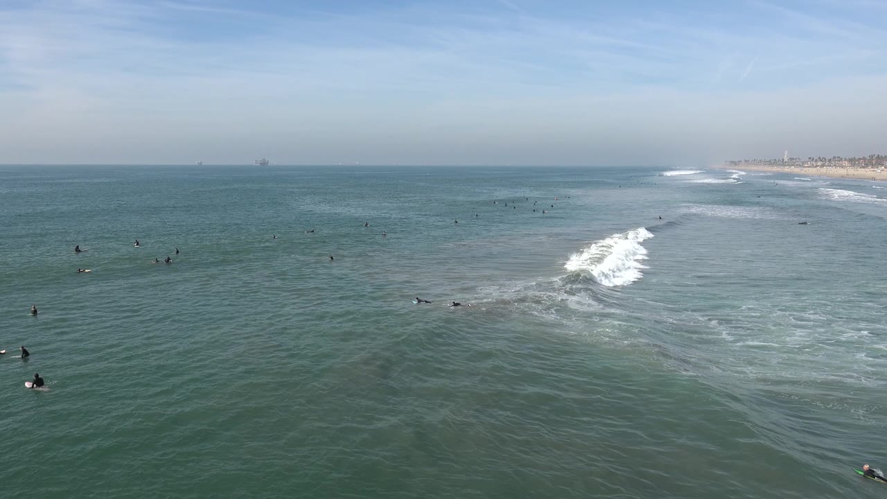 Surf foam rolls through the center while people wait offshore.