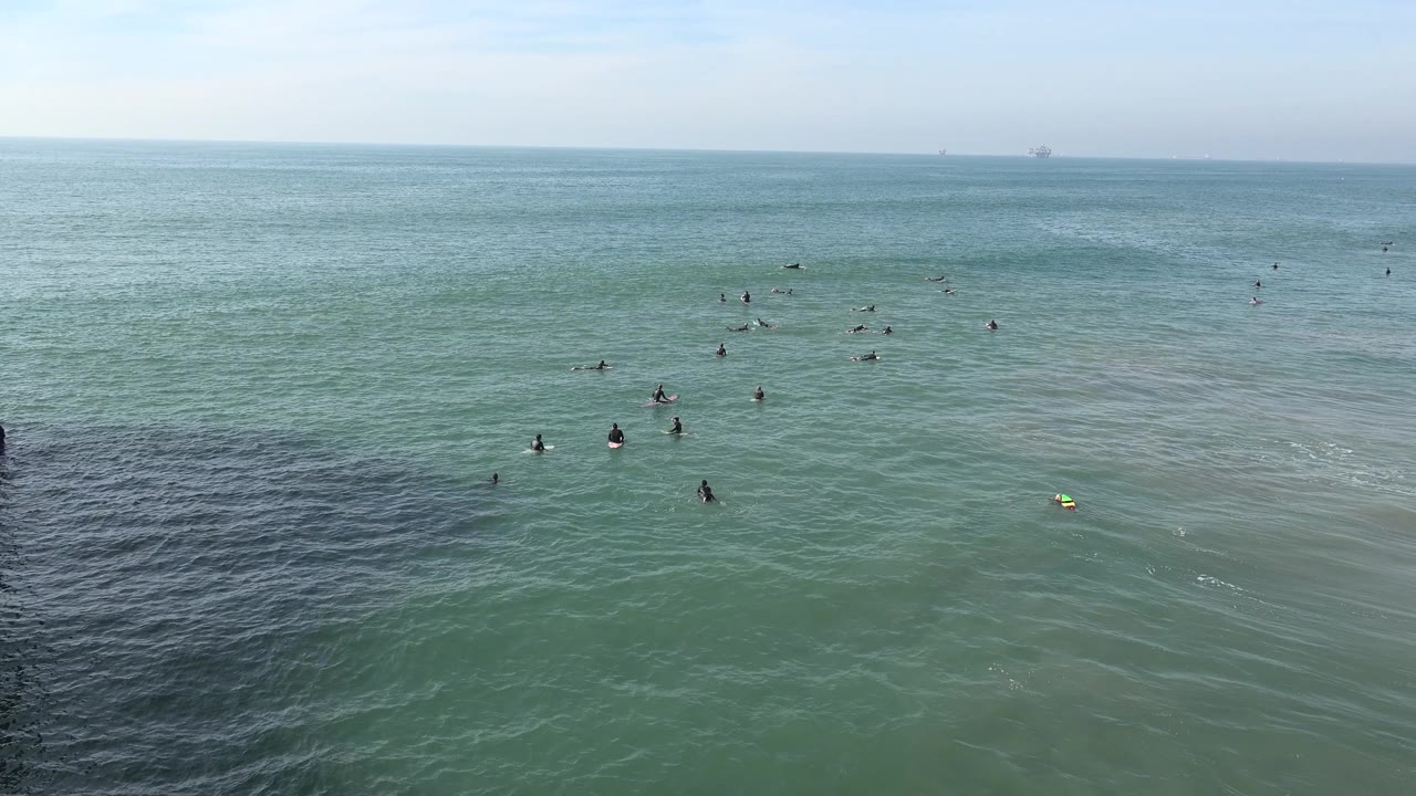 Open ocean with scattered figures, soft wave texture, and darker water at lower left