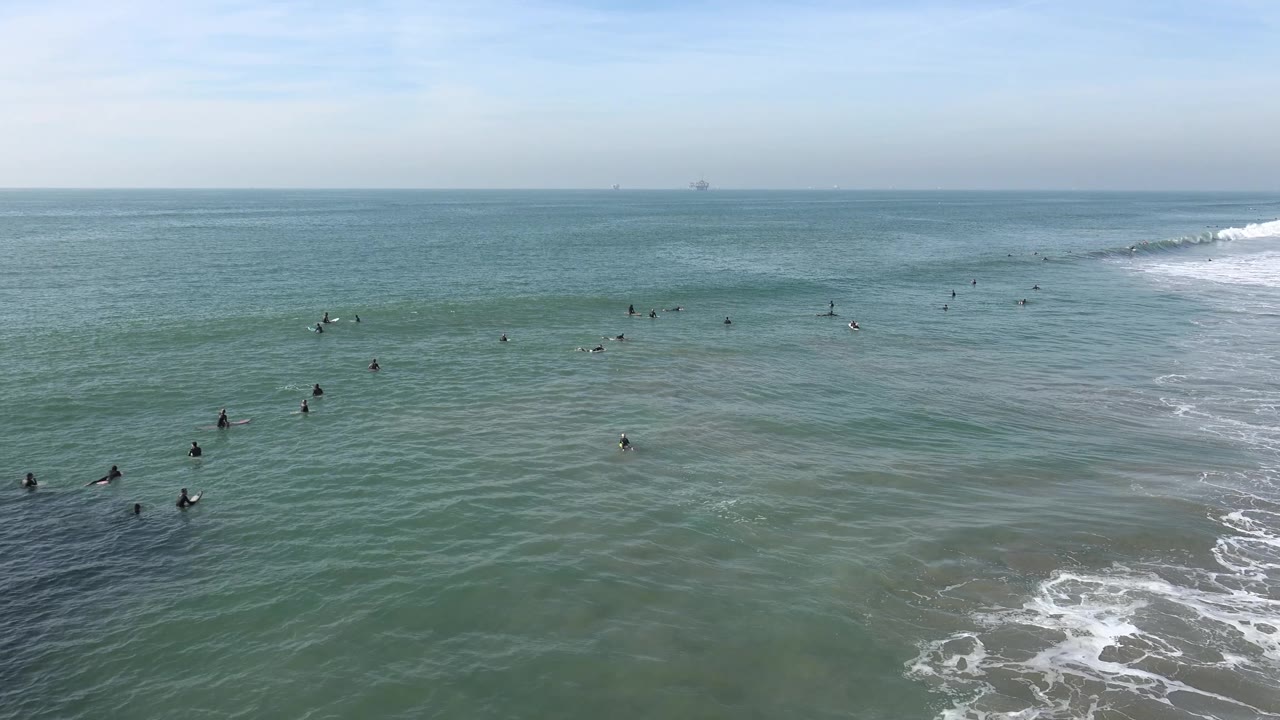 Surfers waiting in green-blue ocean water near a breaking wave