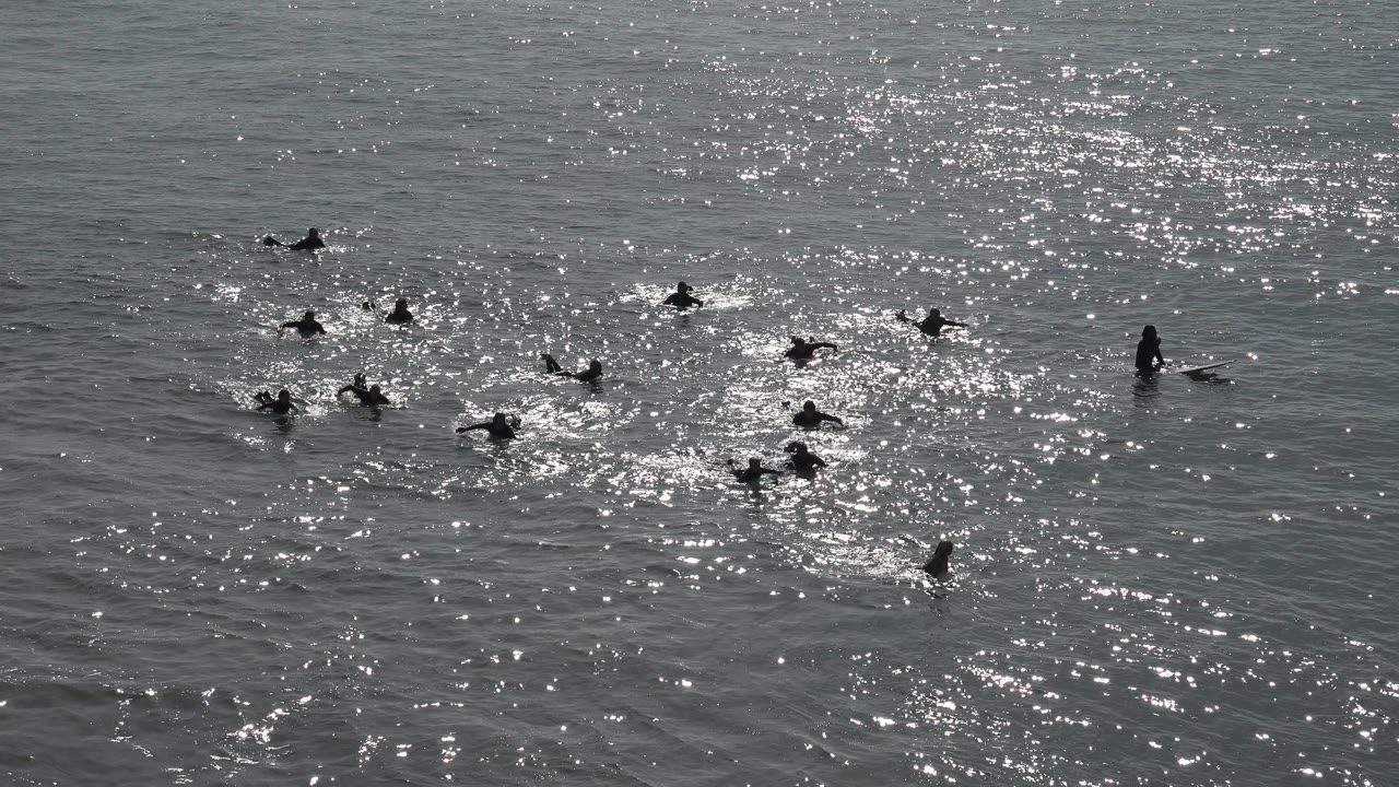 Small group of people floating and paddling in reflective water.