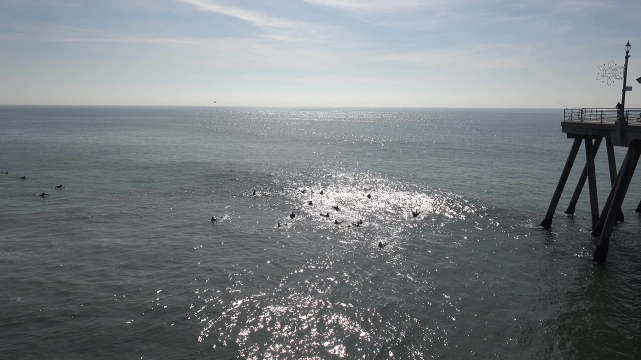 Ocean and pier structure with bright reflection lower in the frame.