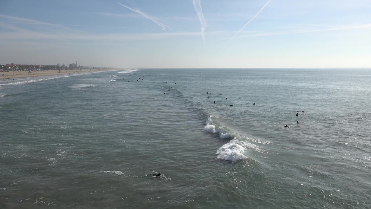 Small figures in the ocean near a diagonal line of breaking surf.