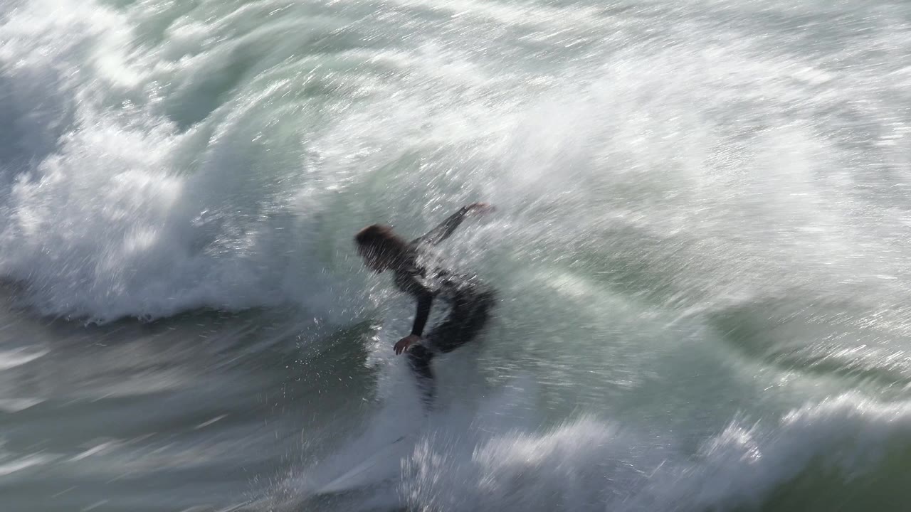 Surfer riding across foamy breaking water.