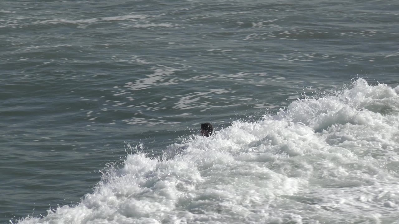 At Huntington Beach, California, the surfer's head appears above a foamy wave crest while open ocean water fills the background.