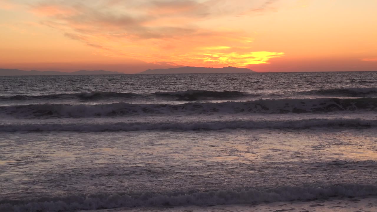 Foamy wave bands and sunset light over the ocean.