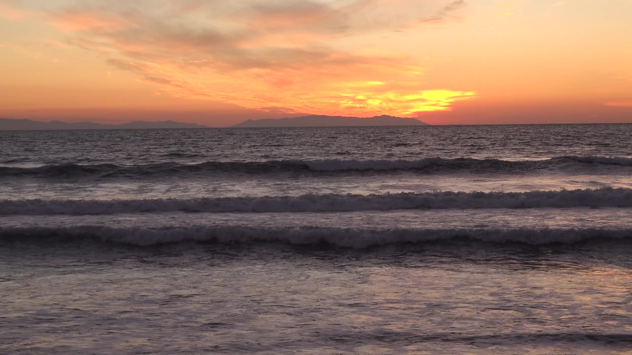 Huntington Beach, California ocean view with pink-orange clouds, dark wave bands, and no visible people.