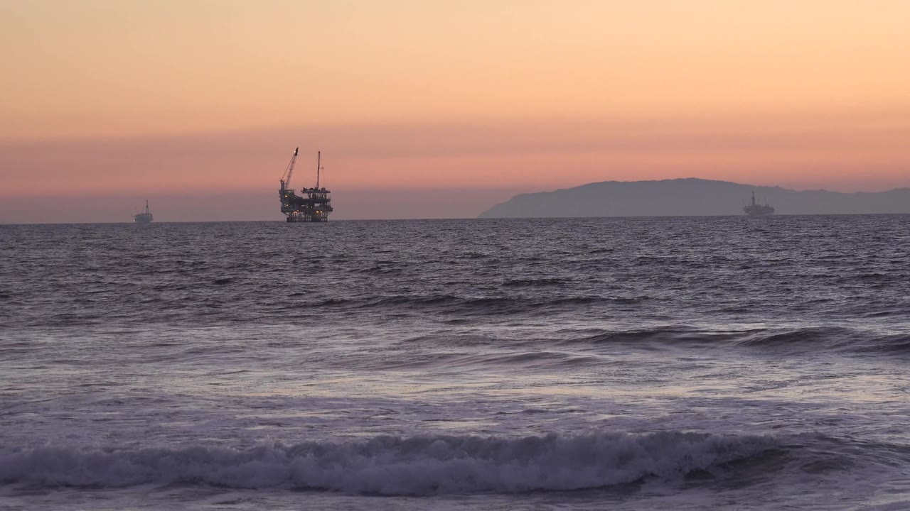 Evening sea surface with a dark offshore structure near the horizon.