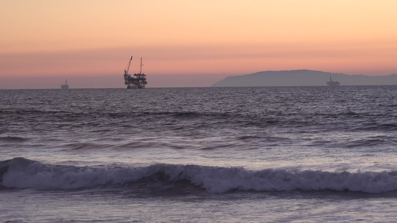 Ocean horizon with distant ships, low waves, and warm morning sky.