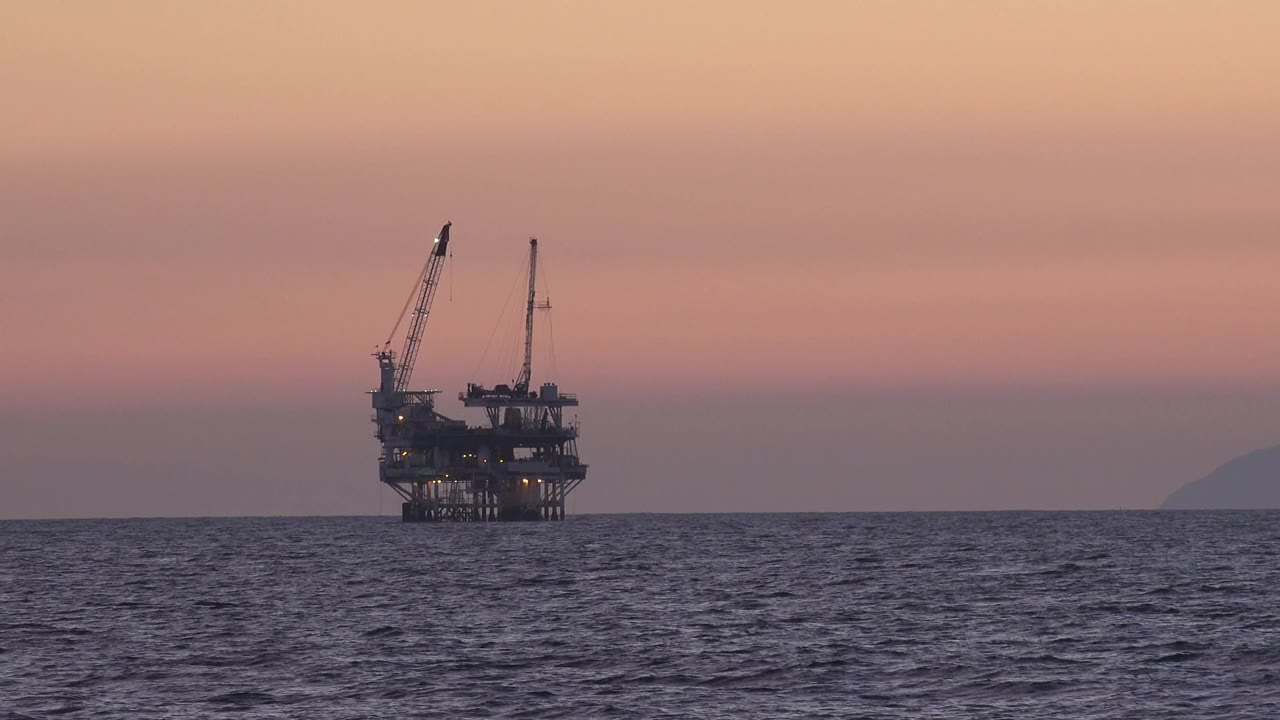 Oil platform silhouetted above dark ocean water