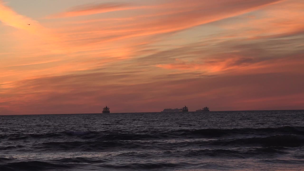 Sunset waves with distant ships on the horizon
