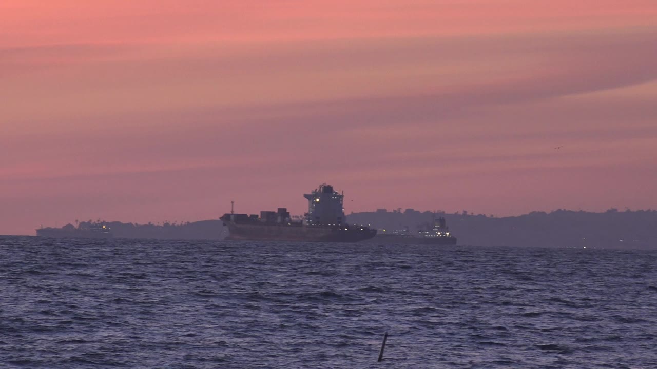 Distant ship on the ocean under a pink sky