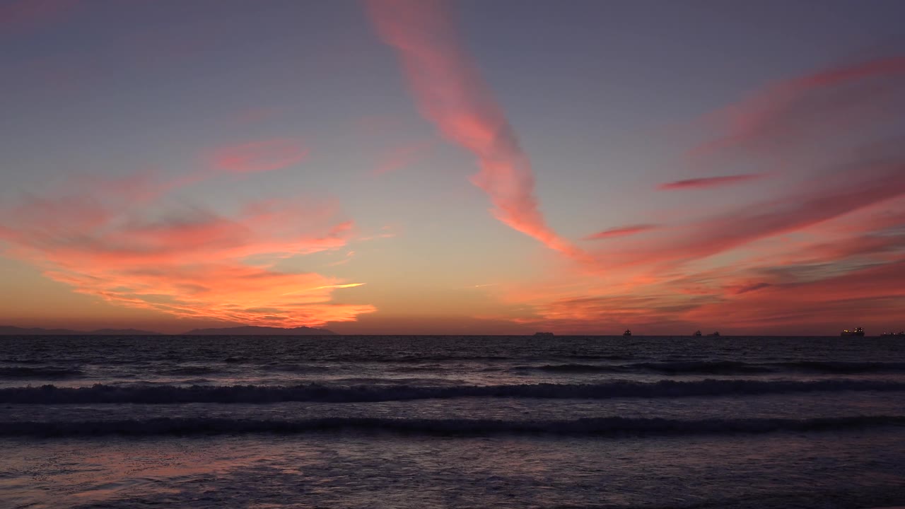 Huntington Beach ocean at 0:02 with layered dark wave bands, distant silhouettes on the horizon, and no visible people.